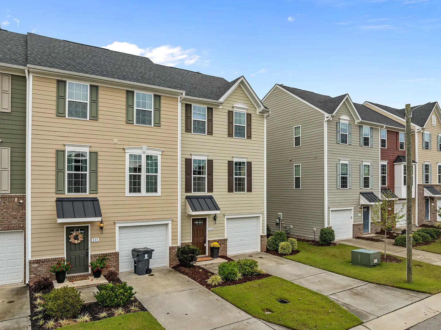 Beautifully landscaped townhome row under blue skies
