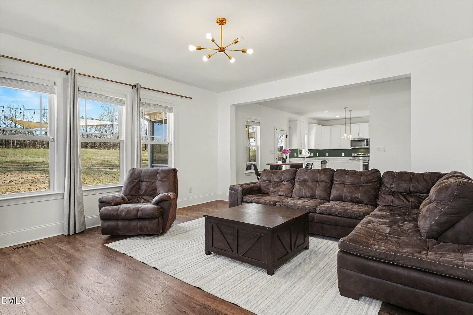 Spacious family room featuring modern chandelier and hardwood floors